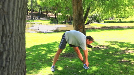 Man-stopping-his-run-to-stretch-in-the-park