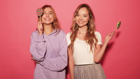 two happy women holding lollipops