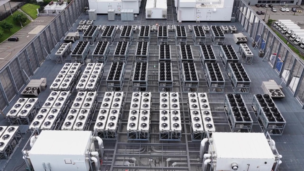 Aerial drone view of large industrial data center cooling facility in the United States, with rows of HVAC units and critical infrastructure supporting cloud computing services. flyover shot.