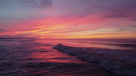 romantic evening at the sea with fiery sunset in the sky, static view with waves crashing