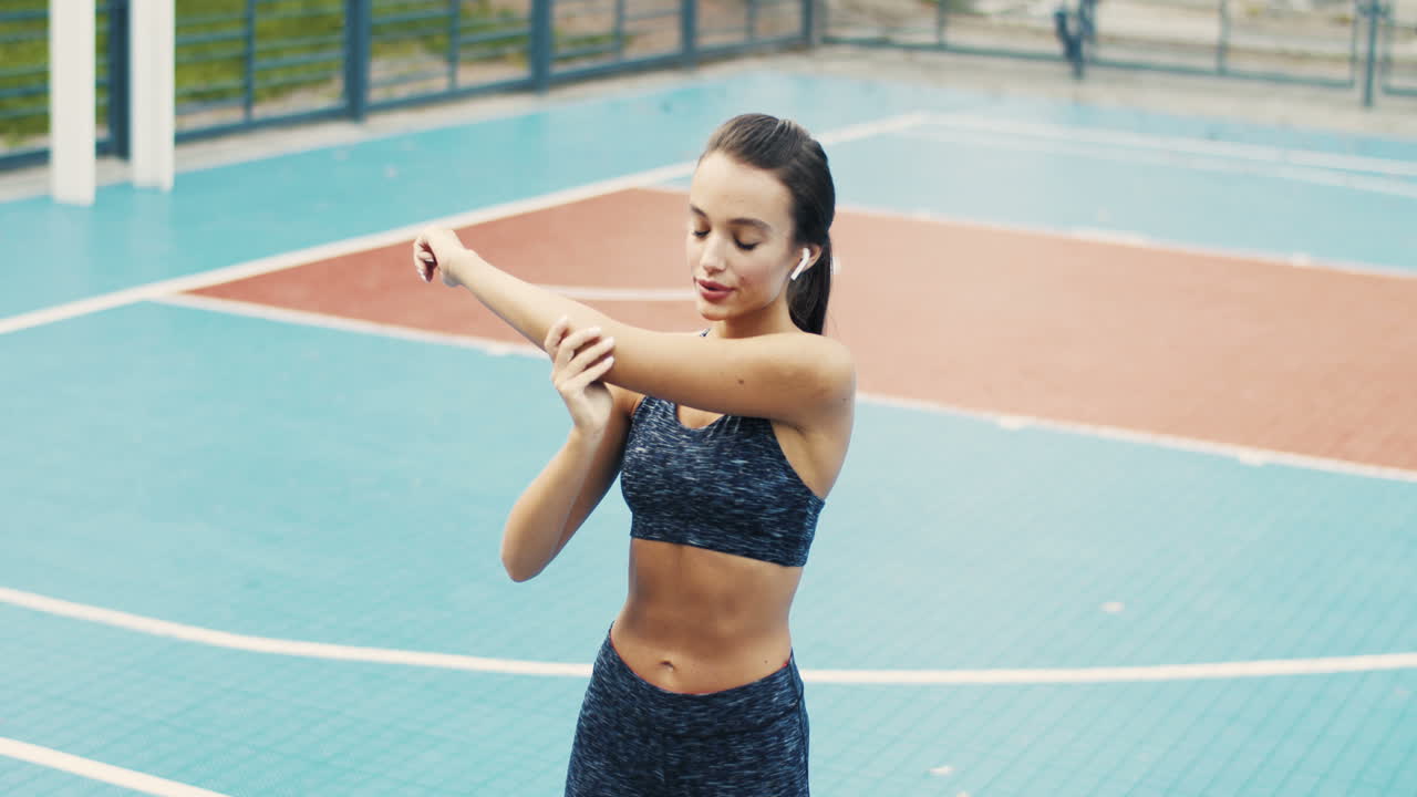 chica deportiva calentando y haciendo ejercicios de estiramiento en la cancha al aire libre en un día de verano