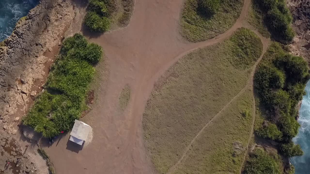 vista aérea suave y mantecosa vuelo vista aérea drone de grandes olas del océano rompiendo en las rocas de la lágrima del diablo en lembongan