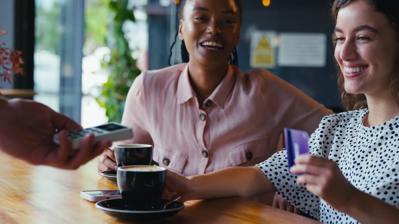 Frau bezahlt im Café kontaktlos mit Karte.