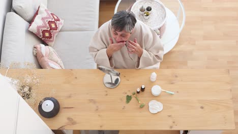 얼굴 크림 을 바르는 목욕복 을 입은 노인 여자