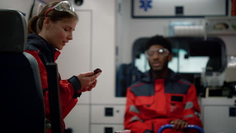 smiling paramedic doctor talking with afro medical worker in emergency car