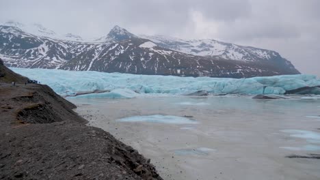 estática, toma del lago en skaftafellsjokull, glaciar turquesa, montañas nevadas en el fondo, en un día nublado, en la costa sur de islandia
