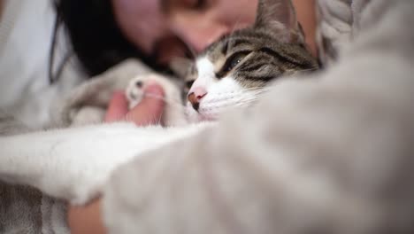 Woman-kissing-and-petting-sleeping-cat-indoor-at-home-laying-in-the-couch