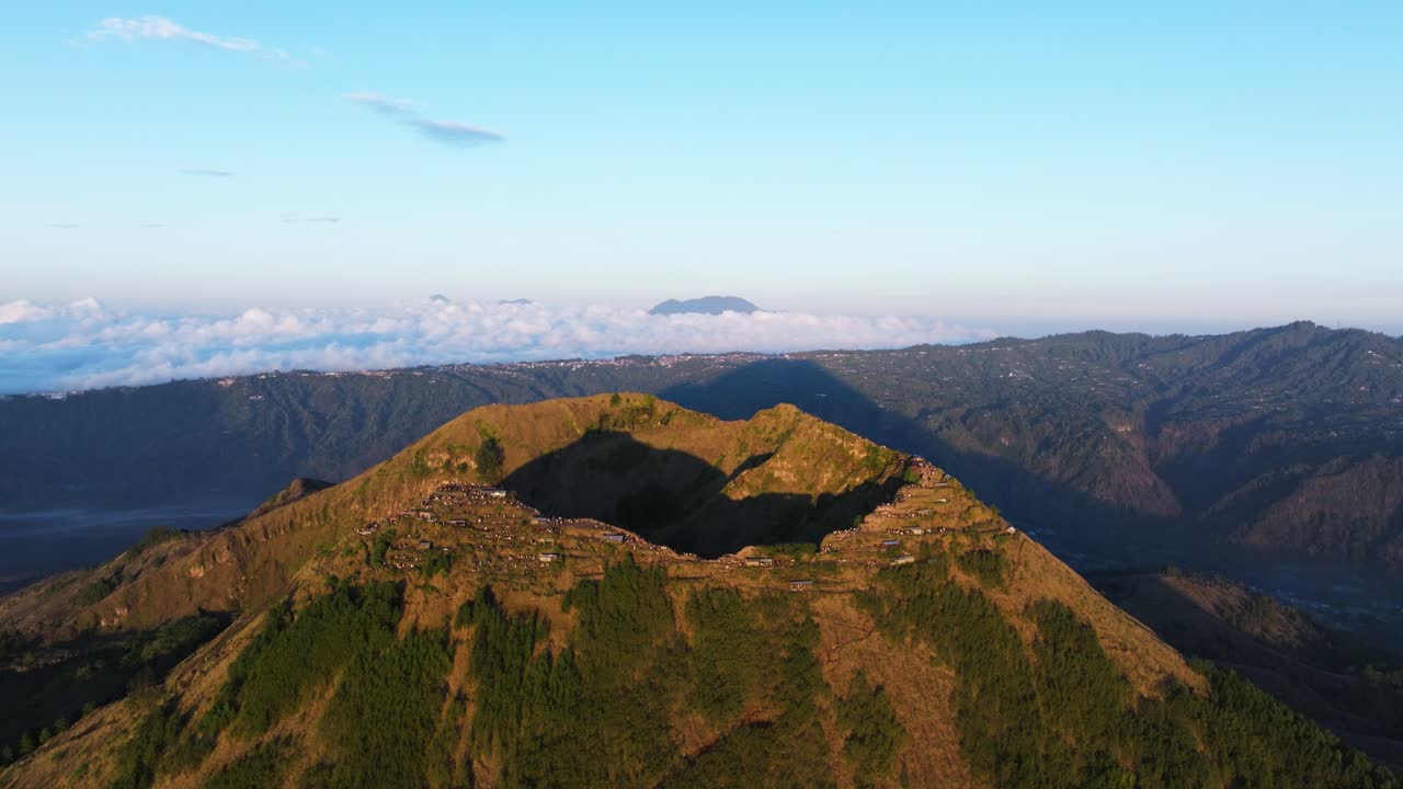 Mount Batur summit crater with hikers enjoying sunrise, volcanic landscape views, soaring aerial hyperlapse