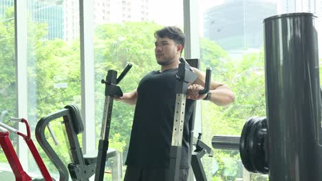 a man performs chest press exercises in a well-lit gym with large windows