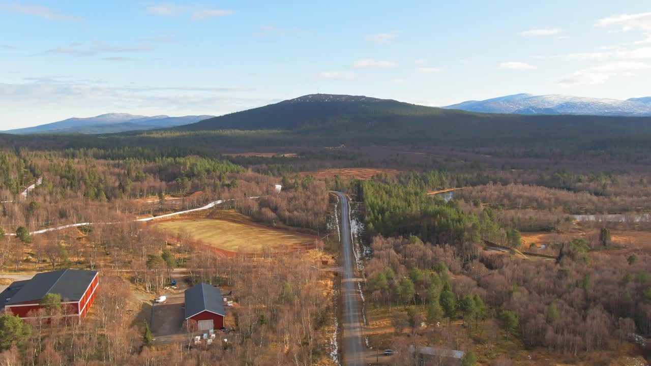 edificios de granja rojos en el bosque de coníferas de abeto alpino sueco cerca de montañas nevadas