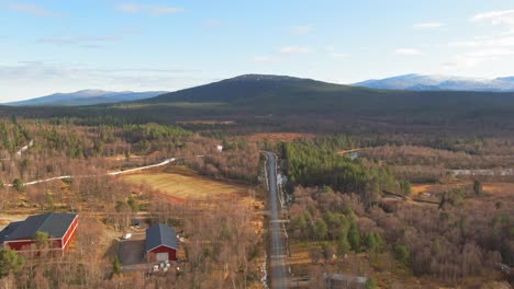 red farm buildings in swedish alpine spruce conifer forest near snowcapped mountains