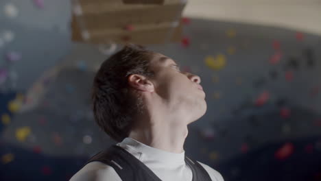 focused young sportsman doing warmup exercises and stretching neck in a bouldering gym