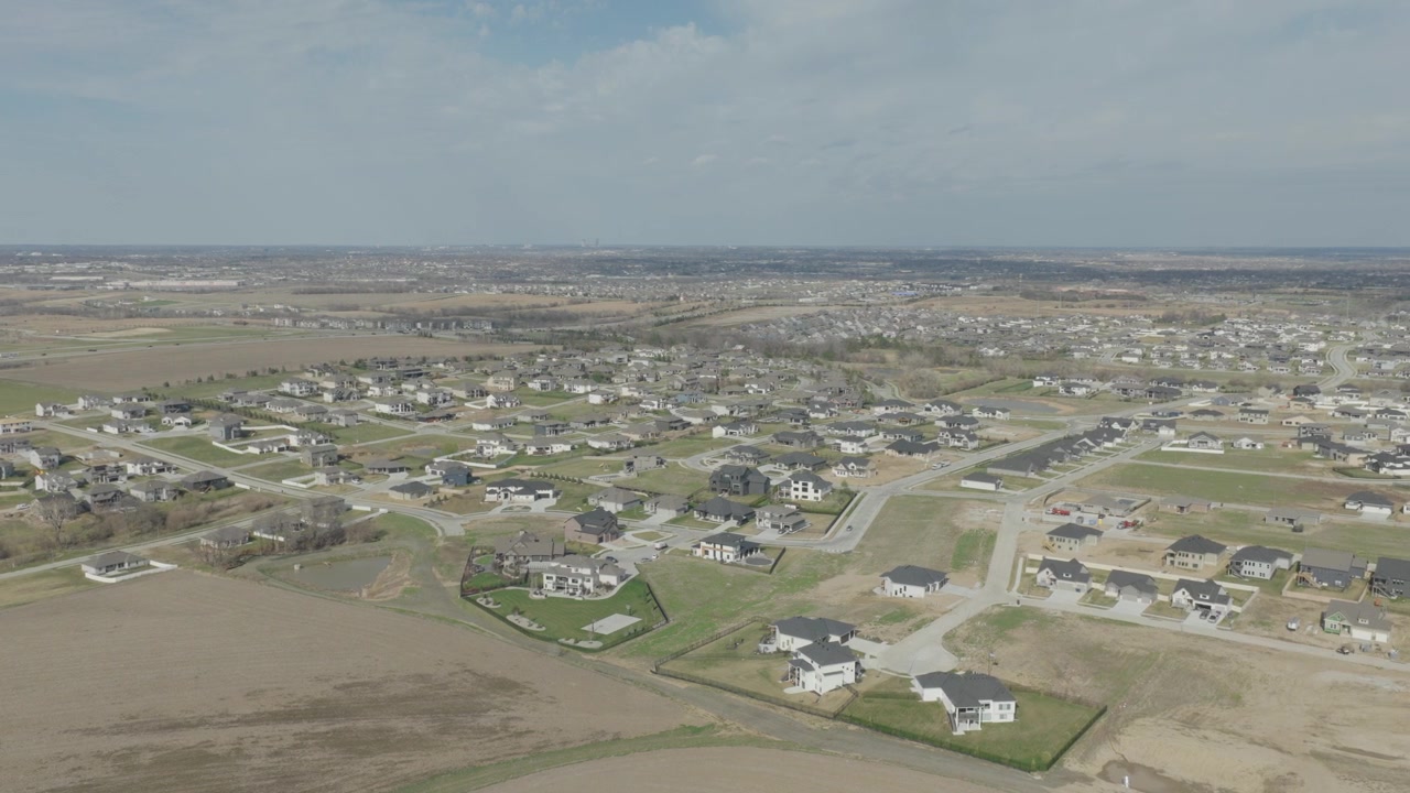 Aerial parallax above Richfield Nebraska reveals luxury homes on vast flat prairie near Omaha, with new street grid surrounded by agricultural fields