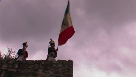 a soldier waves the flag of mexico at a reenactment of the battle of the alamo