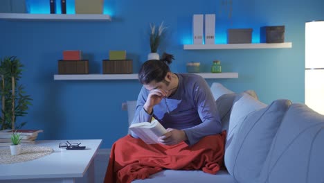 Man-reading-a-book-at-night-looks-tired.