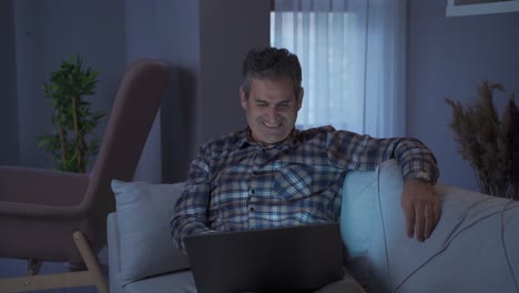 Happy-man-looking-at-laptop-at-home-looking-at-laptop-and-smiling.