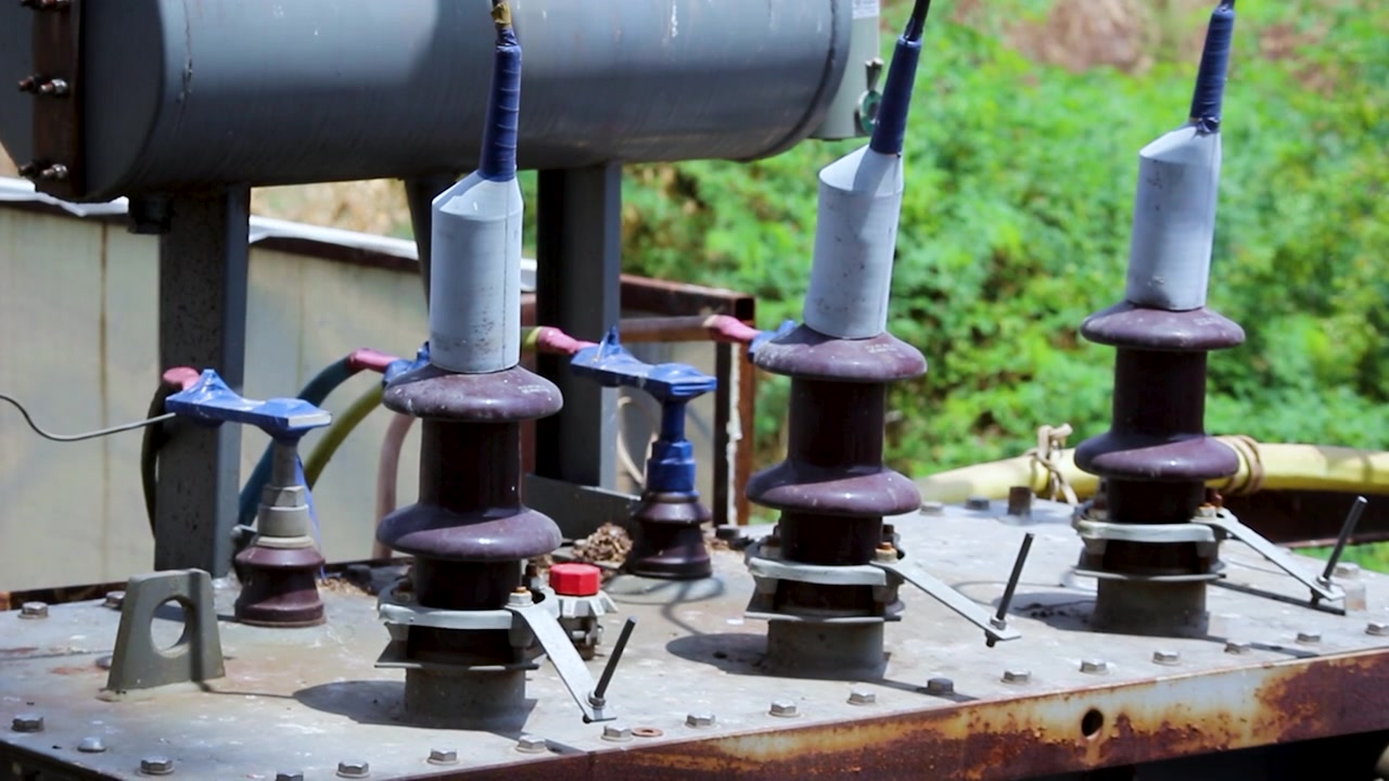 Close-up of transformer bushings and high voltage insulators at an electrical distribution site. Ideal for power grid, electricity infrastructure, utility, and energy industry projects.