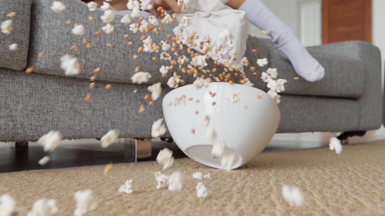Ciotola di popcorn che cade e si rovescia sul pavimento in moquette