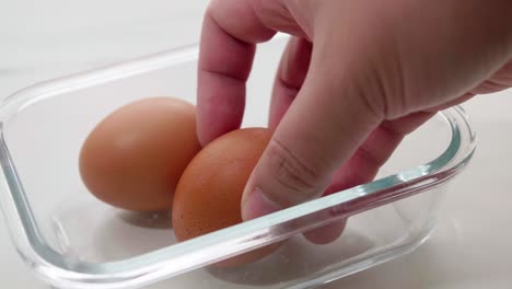 close up male hand putting brown eggs to the carton