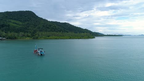 Drone-shot-of-a-half-sunken-boat-in-the-sea-being-towed-by-another-boat