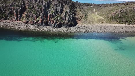 drone aerial over tropical blue water and cliffside moving sideways