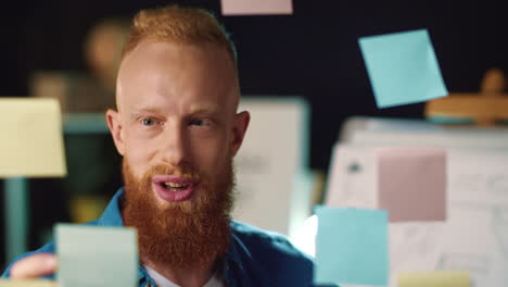 Joyful-businessman-sticking-note-on-board-in-office