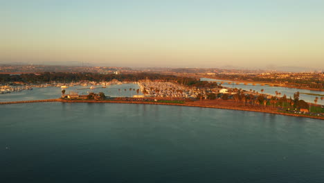 Hermoso-Paisaje-Aéreo-De-La-Bahía-De-La-Misión-Con-Agua-Azul-Y-Cielo-Cálido-De-Puesta-De-Sol-Naranja,-Vista-De-Drones