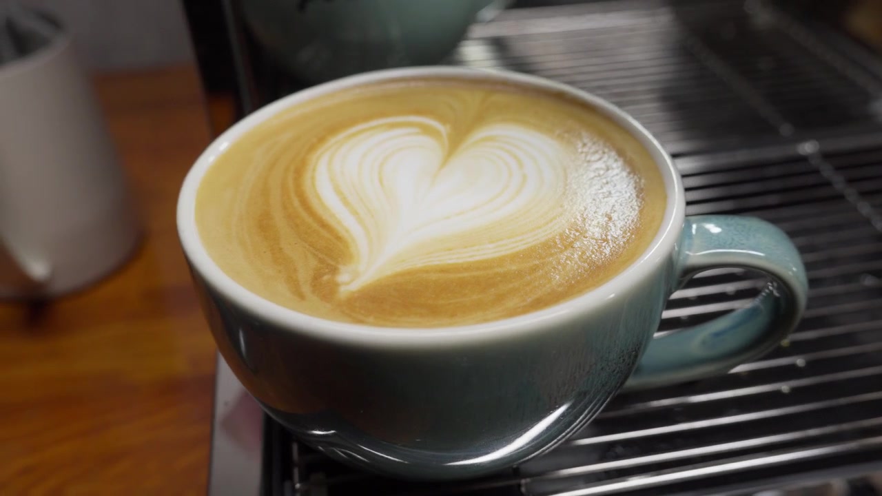Vista de cerca de un latte fresco con arte en forma de corazón sobre espuma de leche en una cafetería