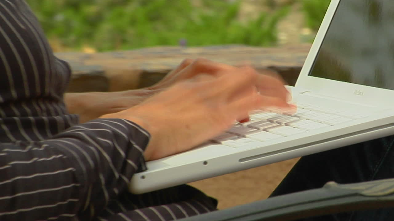 A woman works on a laptop computer in an outdoor setting