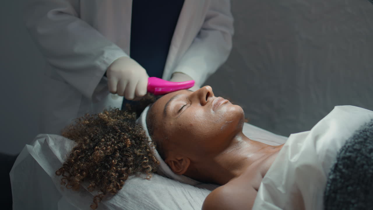 dermatólogo de primer plano masajeando la cara con el pincel. manos frotando crema nutritiva