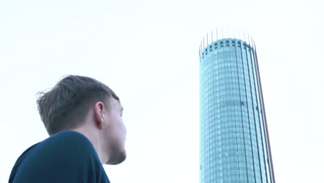 man looking up at a tall skyscraper