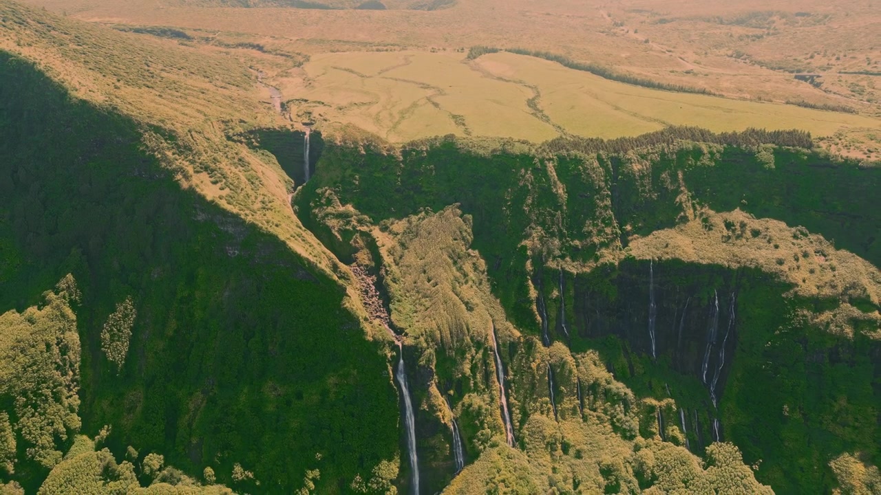 Molteplici cascate scendono da rigogliose scogliere verdi in una profonda valle sull'isola di Flores