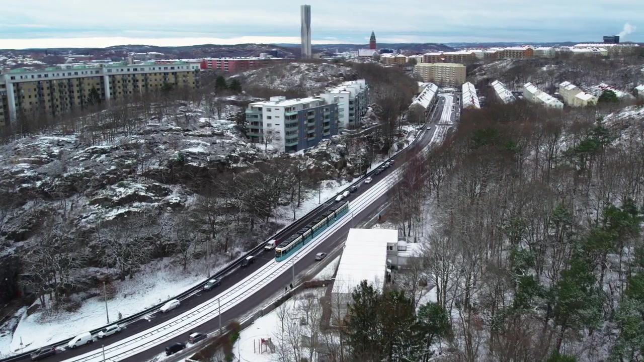 Funivia e traffico automobilistico lungo una strada innevata attraverso il quartenziale residenziale di Majorna, Göteborg