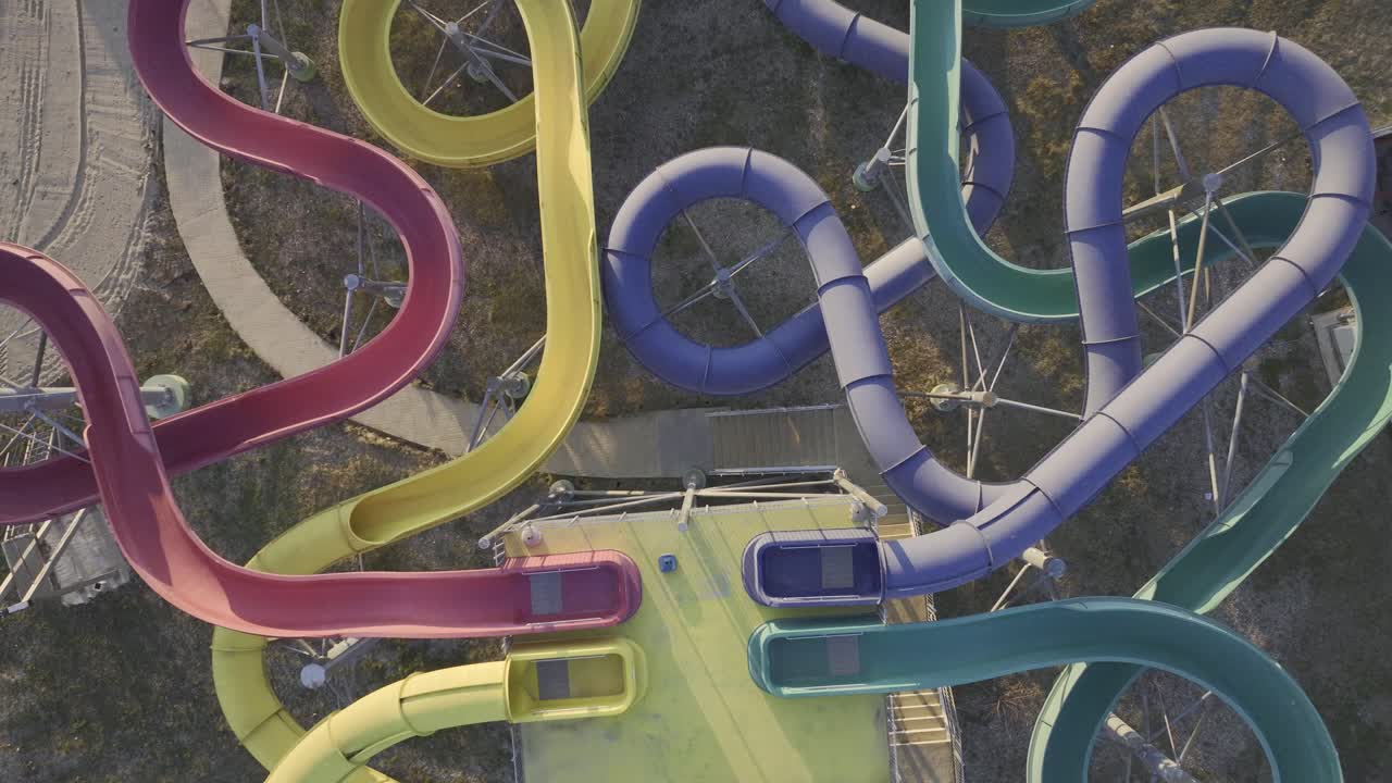 toma aérea de arriba hacia abajo del antiguo parque acuático vacío con toboganes coloridos