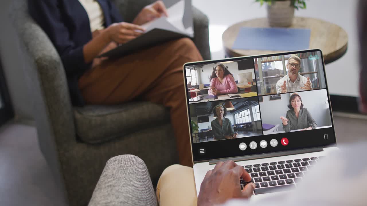 African american man using laptop for video call, with diverse business colleagues on screen