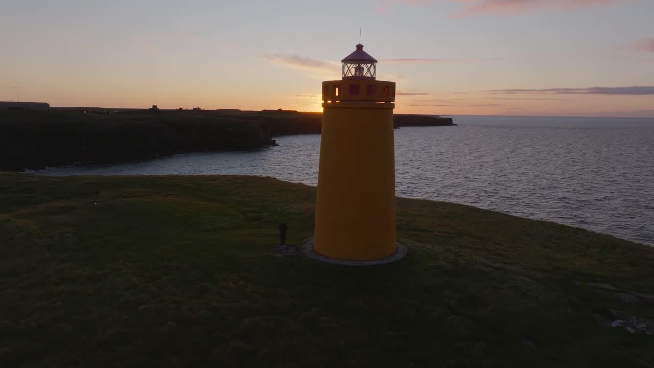 Tampilan drone udara mercusuar kuning Keflavik dan tebing pantai dramatis di tepi samudra