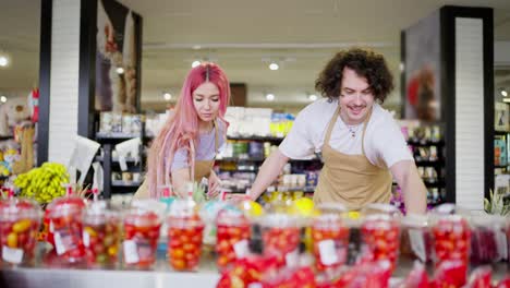 dos trabajadores del supermercado un chico moreno y una chica de cabello rosa hacen un inventario de las mercancías en el departamento de frutas