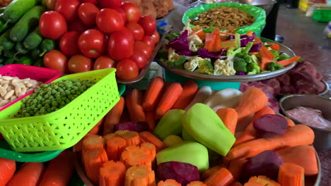 Wide-variety-of-fresh-vegetables-such-as-carrot,-chayote,-tomatoes-and-many-more-on-display-for-sale-with-a-lady-hand-in-the-background