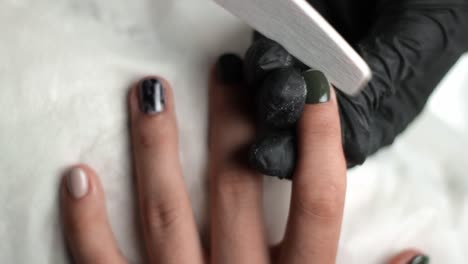 manicurist carefully filing down the edges of a clients nails after they have been polished