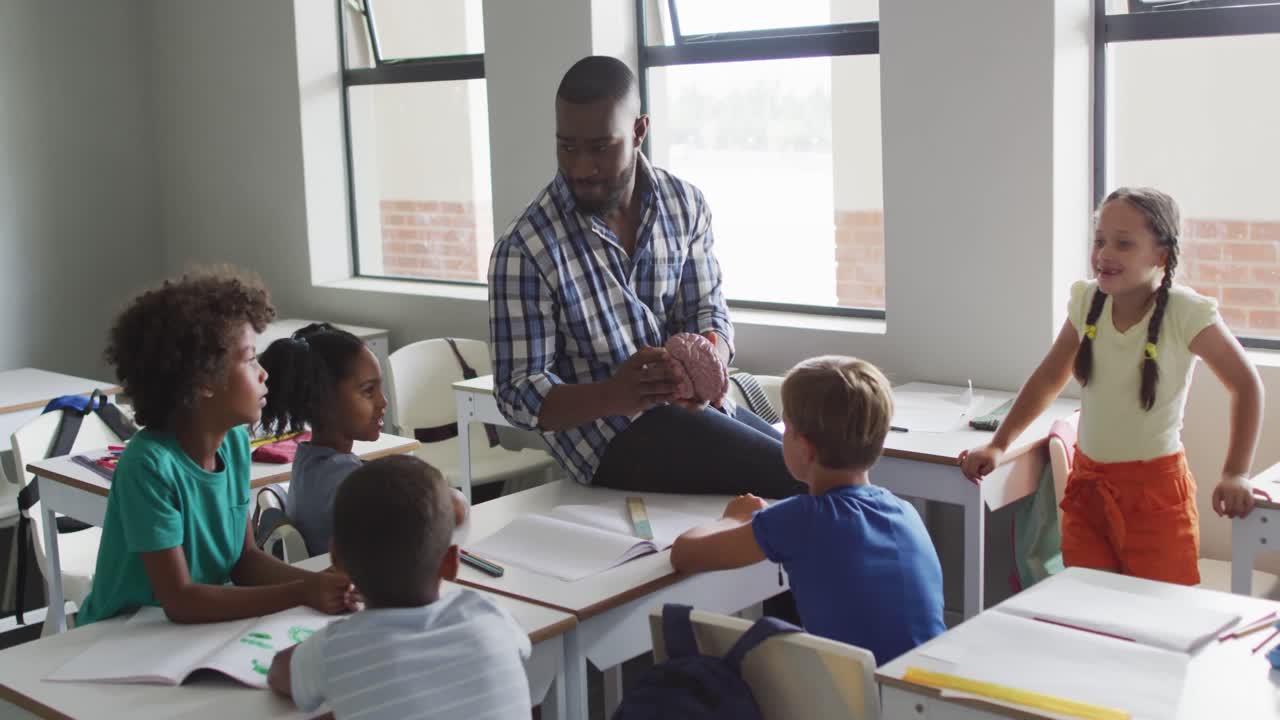 Video of happy african american male teacher and class of diverse pupils during biology lesson