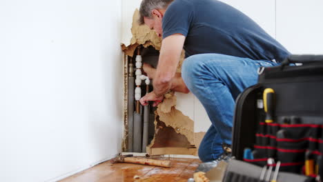 domestic plumber with tools repairing leaking pipe