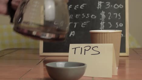 pouring takeout coffee in cafe near tipping jar medium shot