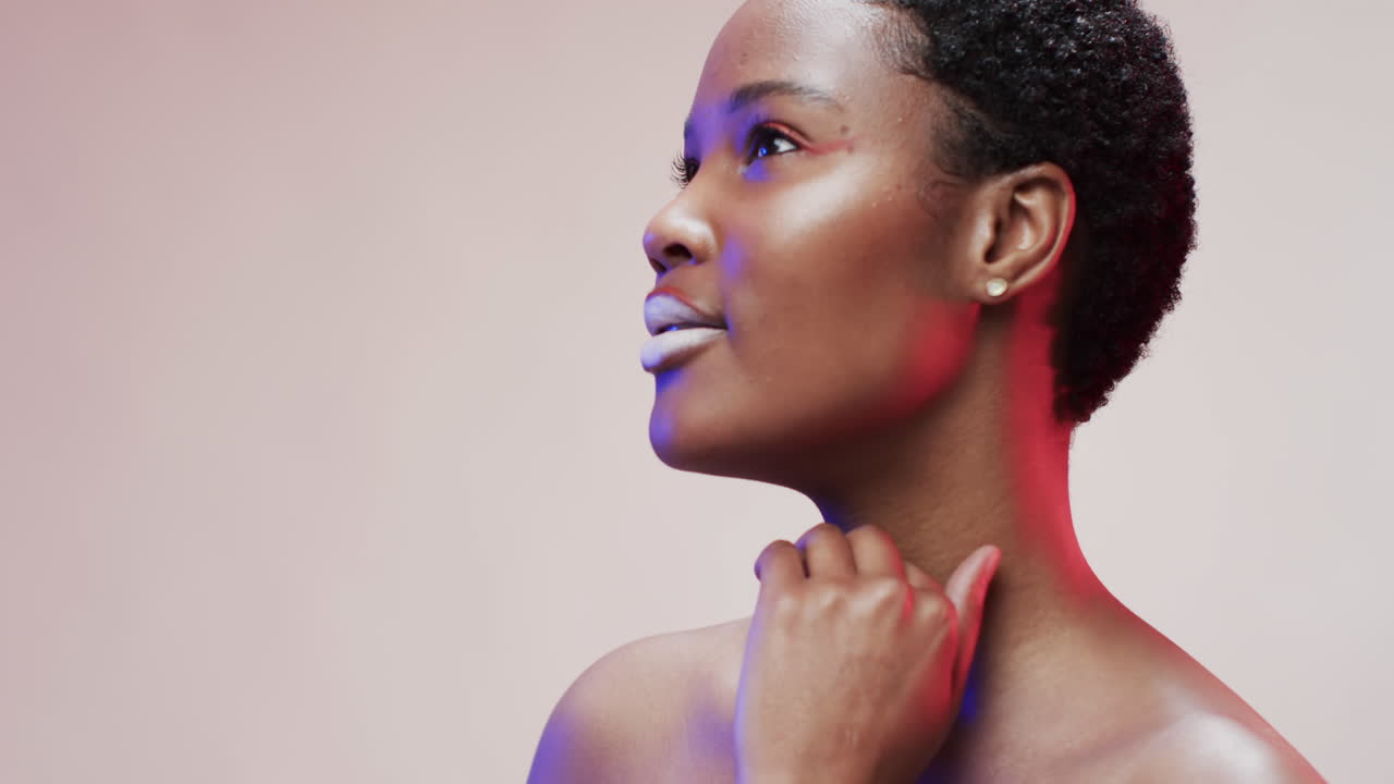 Femme afro-américaine aux cheveux foncés courts dans une lumière bleue et rose avec espace de copie, au ralenti