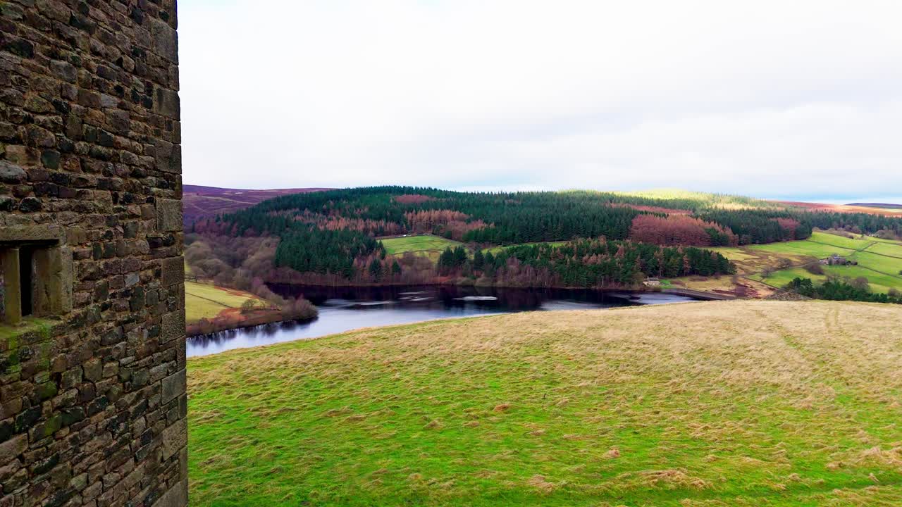 Old derelict castle, monument, disused stone tower, with people walking around and flying a drone