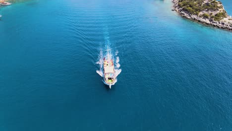 Drone-fly-over-a-bay-in-the-Mediterranean-over-a-yacht-sailing-between-islands-covered-in-green-trees-under-a-blue-sky