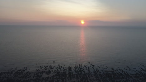 Toma-Aérea-Lenta-Y-Alta-De-La-Antigua-Playa-De-Hunstanton-Impresionante-Hermosa-Puesta-De-Sol-Con-Mar-En-Calma-Con-Pequeñas-Olas-En-La-Costa-Este-Del-Norte-De-Norfolk,-Reino-Unido