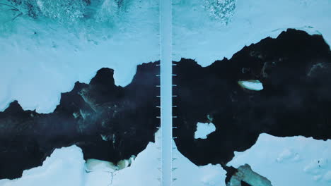 top-down view of bridge spanning the vikakongas river during winter in finland