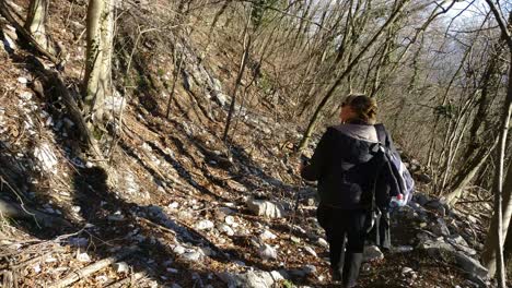 a woman with blond hair walking down the path on a mountain with scandinavian sticks