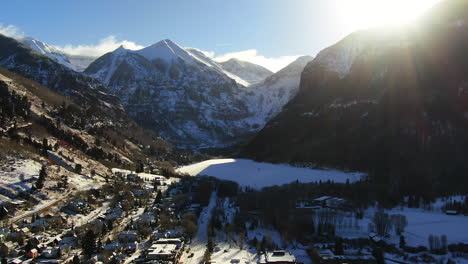 Aerial-Cinematic-Drone-view-of-Telluride-mountain-ski-resort-downtown-Colorado-of-scenic-mountains-landscape,-lake-and-historic-buildings-early-sun-light-mid-winter-pan-forward-reveal-movement