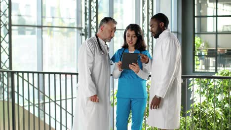 mixed-races doctors talking and using tablet device in clinic